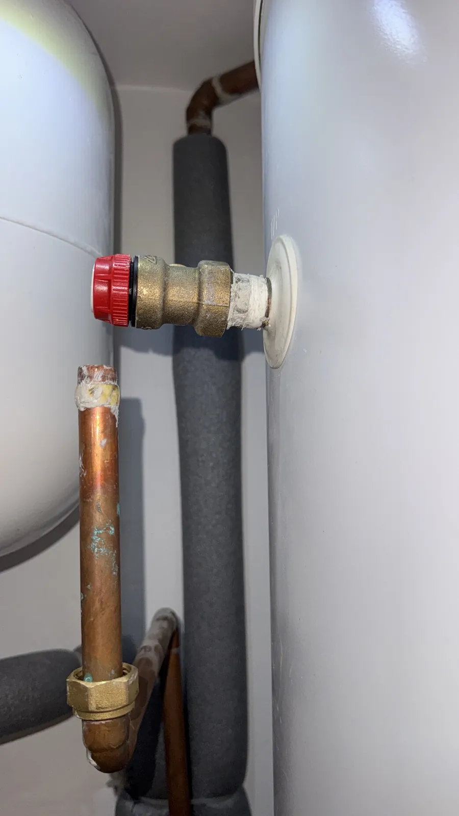 Brass temperature and pressure relief valve with a red cap fitted to the side of an unvented cylinder